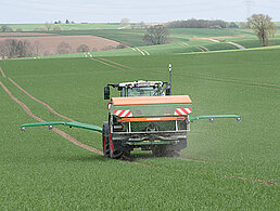 Fendt-Traktor mit Amazone Düngerstreuer und NEXT GreenSeeker fährt über ein Feld, fotografiert von hinten